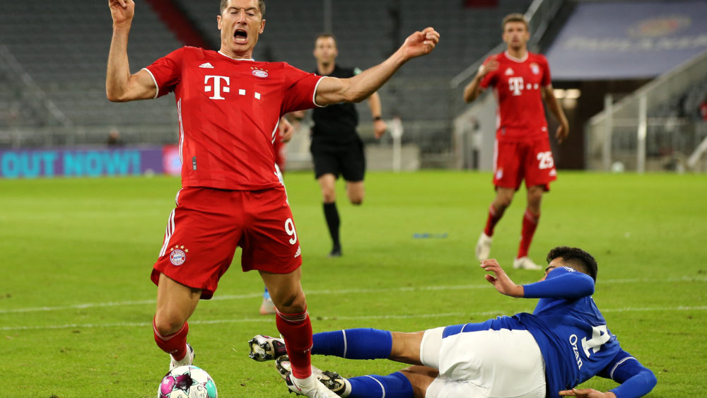 MUNICH, GERMANY - SEPTEMBER 18: Robert Lewandowski of Bayern Munich is tackled and fouled for a penalty by Ozan Kabak of Schalke 04 during the Bundesliga match between FC Bayern Muenchen and FC Schalke 04 at Allianz Arena on September 18, 2020 in Munich, Germany. Fans are set to return to Bundesliga stadiums in Germany despite to the ongoing Coronavirus Pandemic. Up to 20% of stadium's capacity are allowed to be filled. Final decisions are left to local health authorities and are subject to club's hygiene concepts and the infection numbers in the corresponding region. The match in Munich is played behind closed doors due to the high number of new Covid-19 cases in the city of Munich. (Photo by Alexander Hassenstein/Getty Images)