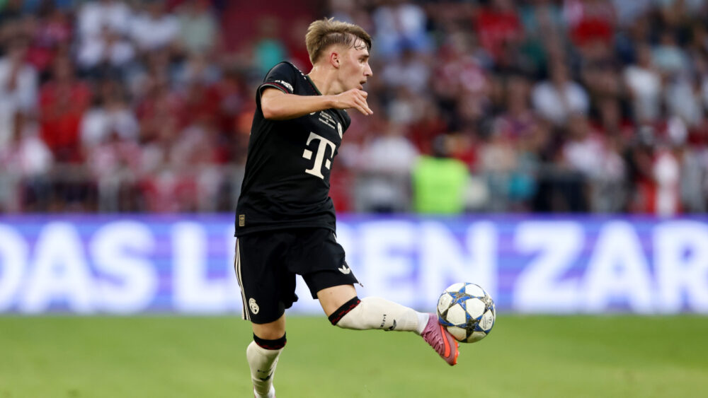 Lennart Karl im schwarzen Trikot des FC Bayern München. Zu sehen ist, wie er den Ball mit der Außenseite seines Fußes elegant annimmt.