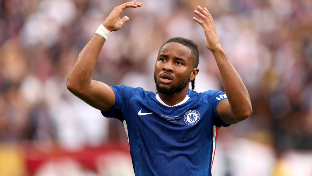Christopher Nkunku im Trikot des FC Chelsea in blau, er reißt die Arme hoch. Im Hintergrund Publikum. Spielt Nkunku bald für den FC Bayern?