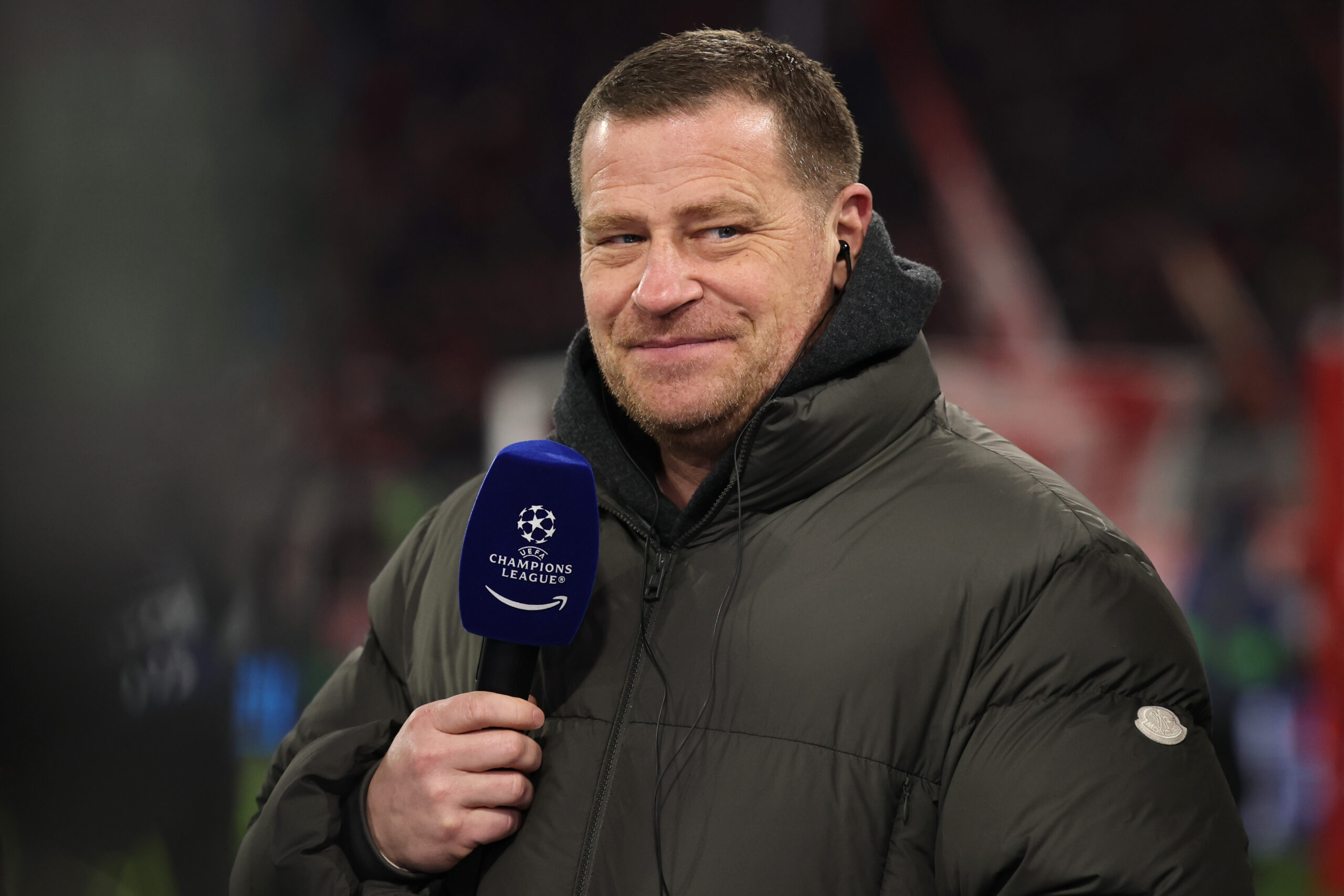 Max Eberl in Winterjacke am Champions-League-Mikrofon vor einem Spiel des FC Bayern München.