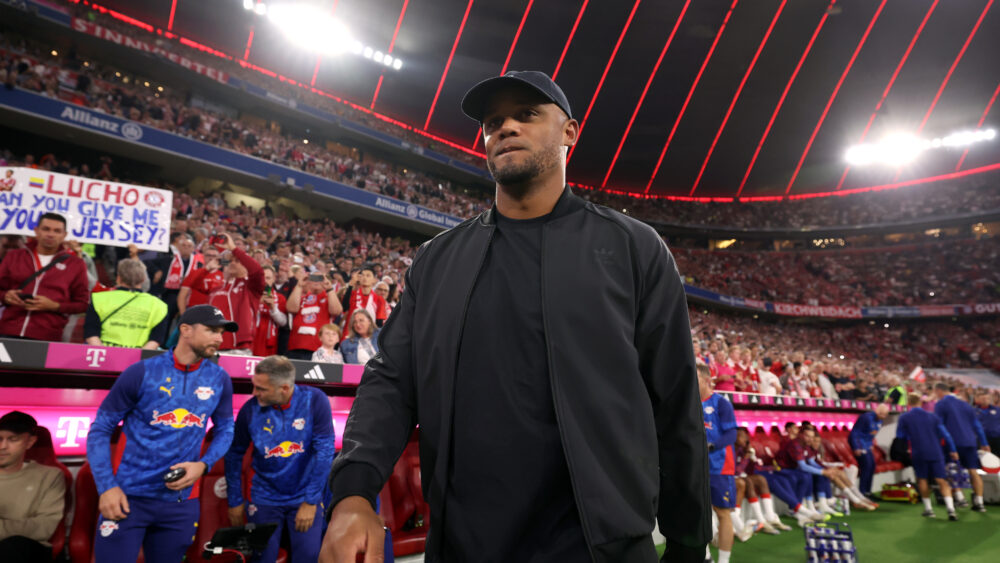 Vincent Kompany (Trainer des FC Bayern) in dunkler Kleidung. Im Hintergrund die Tribünen der Allianz Arena.