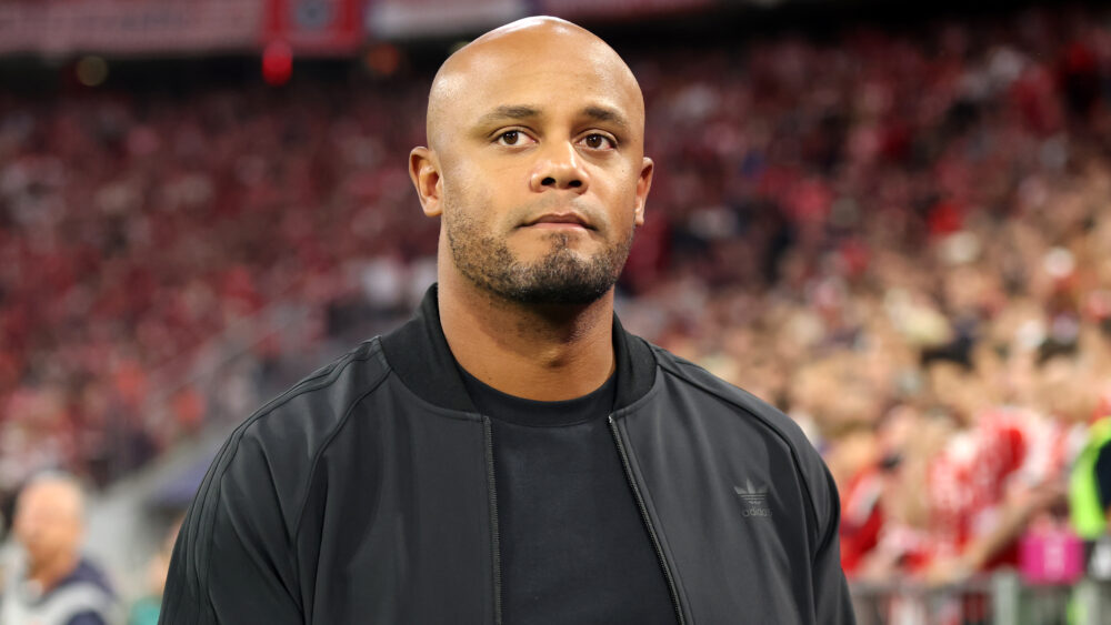 Vincent Kompany vom FC Bayern in dunkler Kleidung, hinter ihm das Publikum in der Allianz Arena.