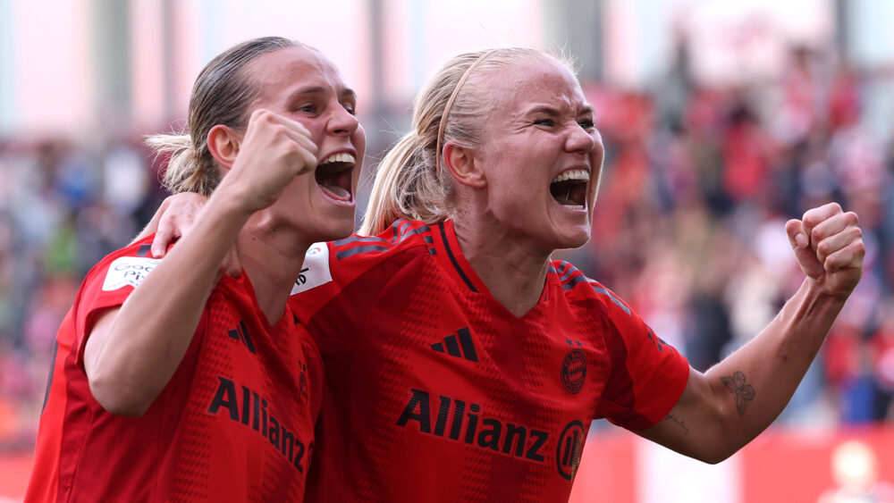 Klara Bühl und Pernille Harder freuen sich über ein Tor. Sie schreien mit freudigen Gesichtern in Richtung Fans und ballen die Fäuste. Sie tragen dabei das rote Heimtrikot der FC Bayern Frauen.