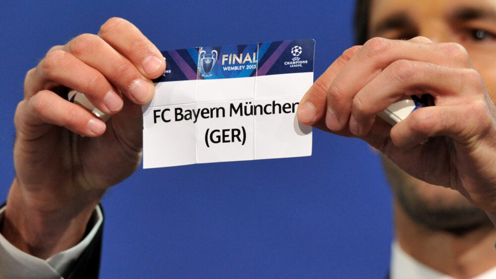 Auf einem Papier steht "FC Bayern München", Ruud van Nistelrooy hält das Papier fest.