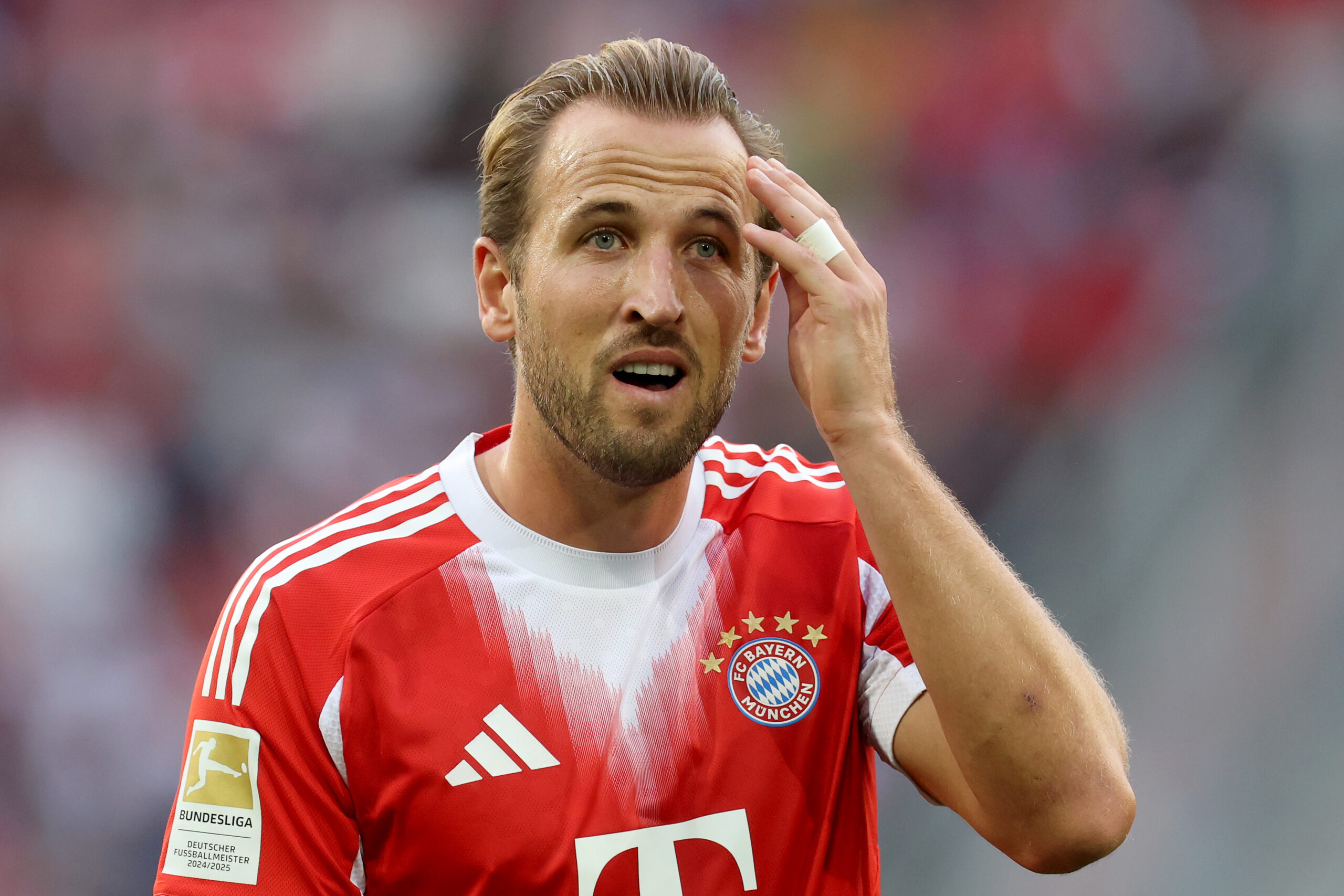 Harry Kane im Trikot des FC Bayern München. Er fässt sich an die Stirn.