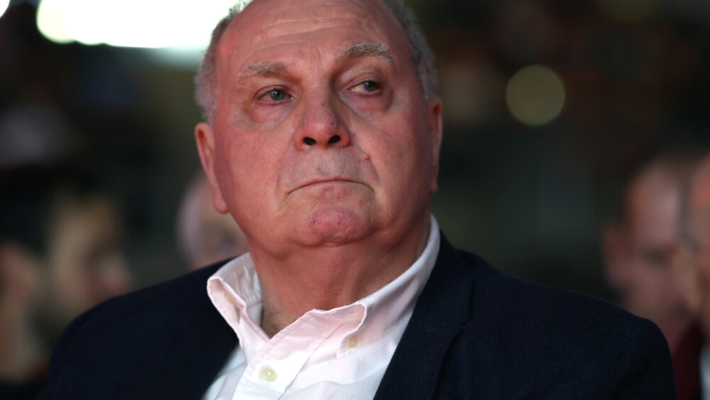 Uli Hoeneß vom FC Bayern in schwarzer Kleidung und weißem Hemd, er schaut ziemlich ernst.