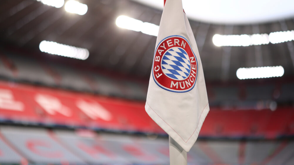Eine Fahne in der Allianz Arena, auf der das Logo des FC Bayern München zu sehen ist.