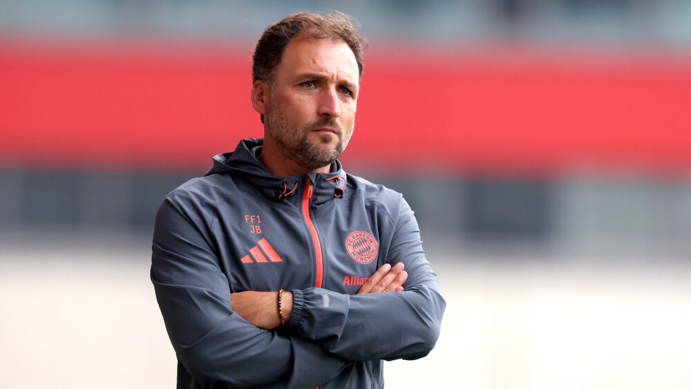 José Barcala von den FC Bayern Frauen steht mit eingeschränkten Armen da.