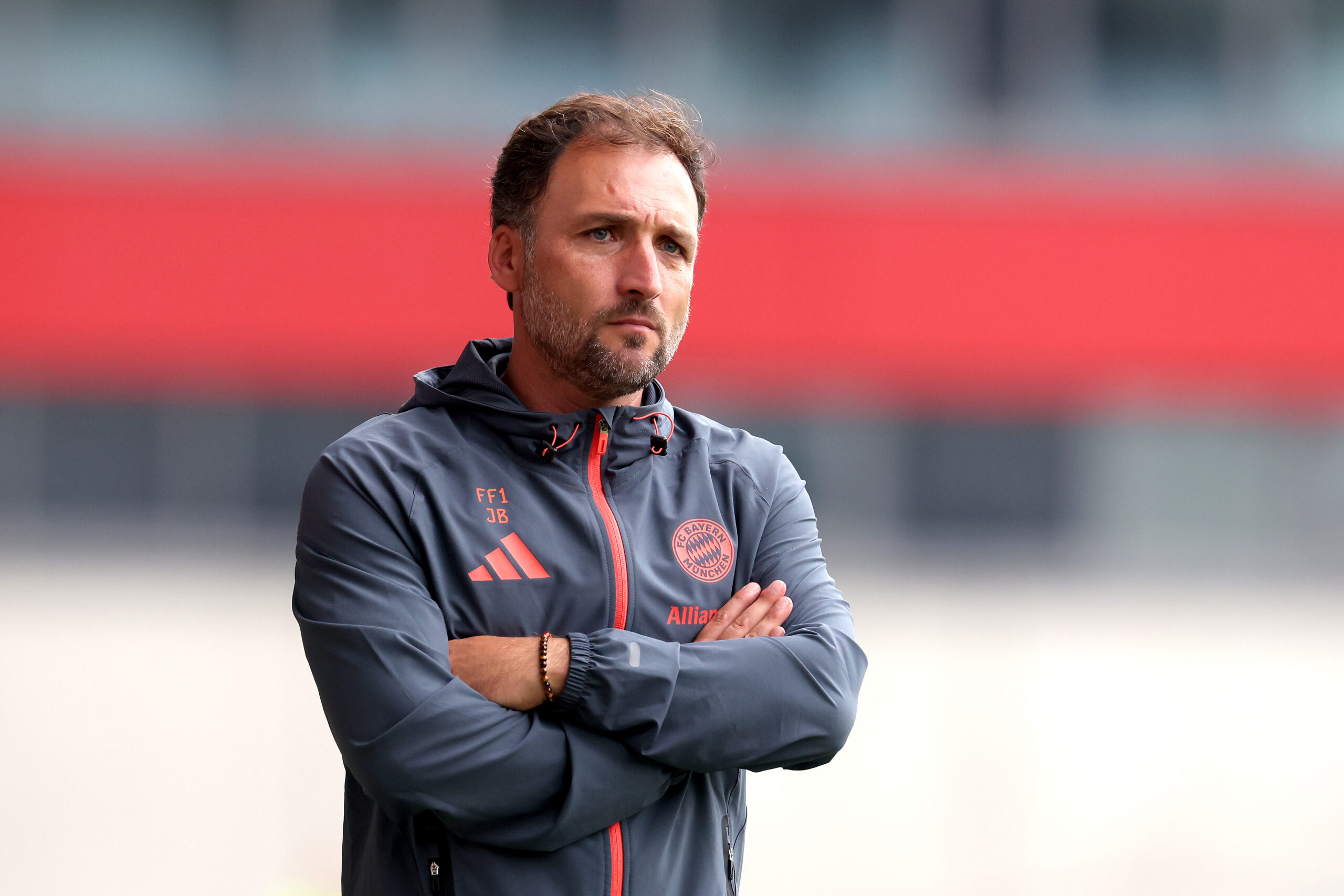 José Barcala von den FC Bayern Frauen steht mit eingeschränkten Armen da.