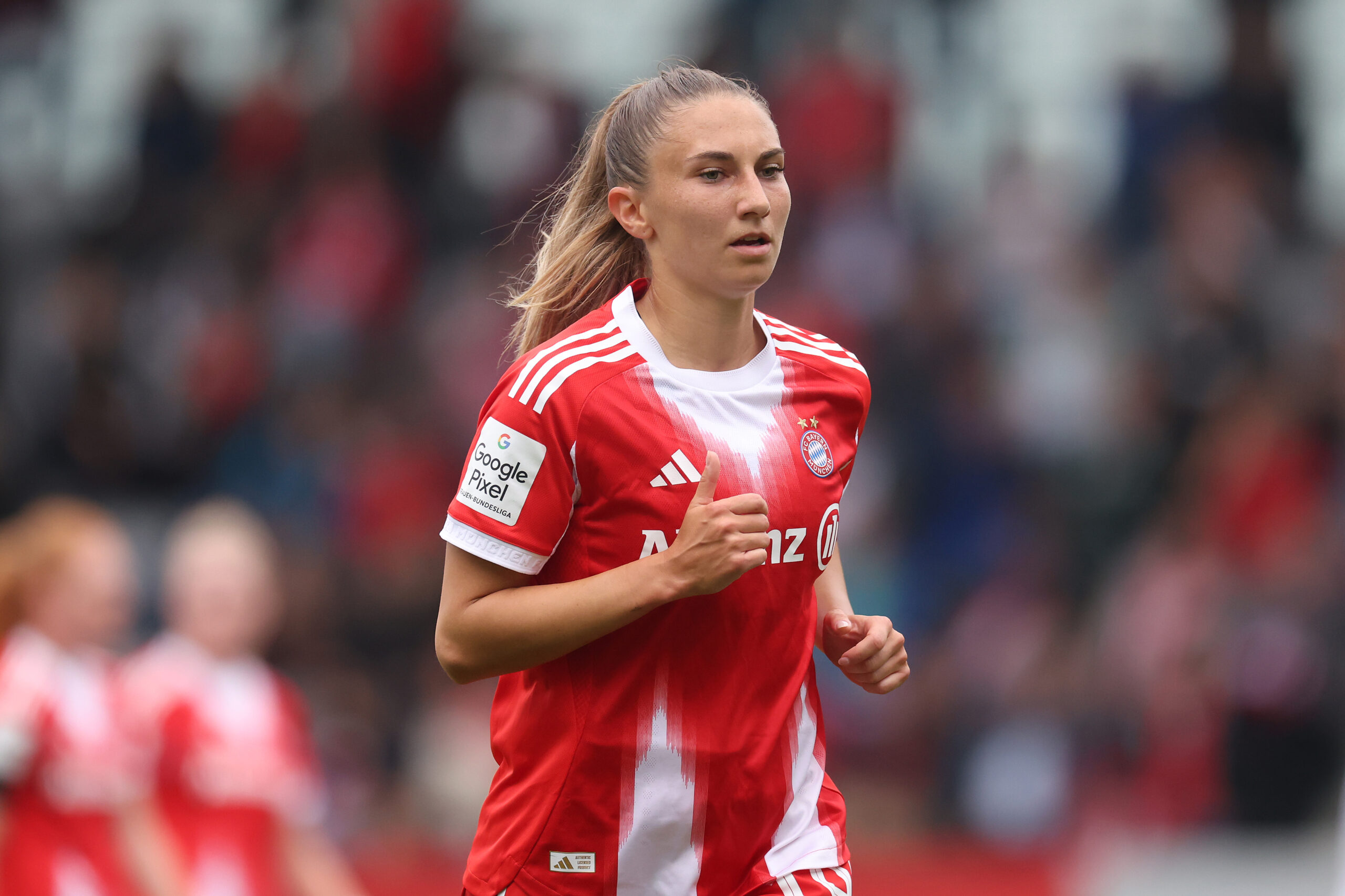 Katharina Naschenweng trägt das rot-weiße Trikot der FC Bayern Frauen und joggt offenbar.