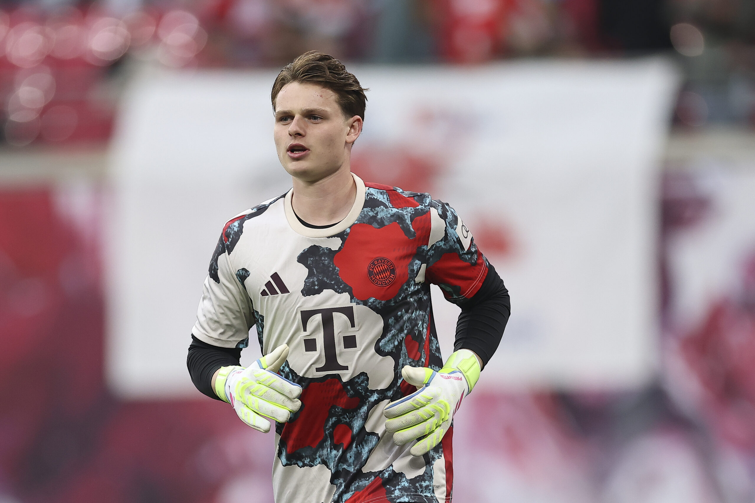Jonas Urbig macht sich im Trainingsshirt des FC Bayern München warm.