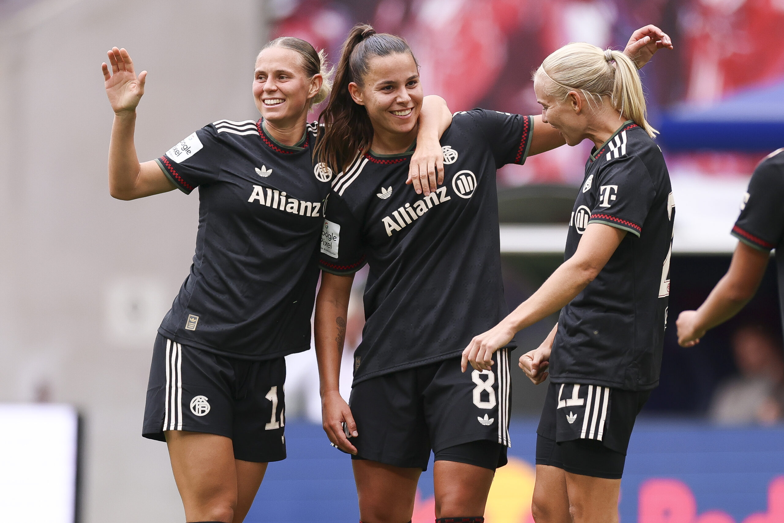 Klara Bühl, Lena Oberdorf und Pernille Harder im dunklen Auswärtstrikot der FC Bayern Frauen. Sie lachen und jubeln über ein Tor.