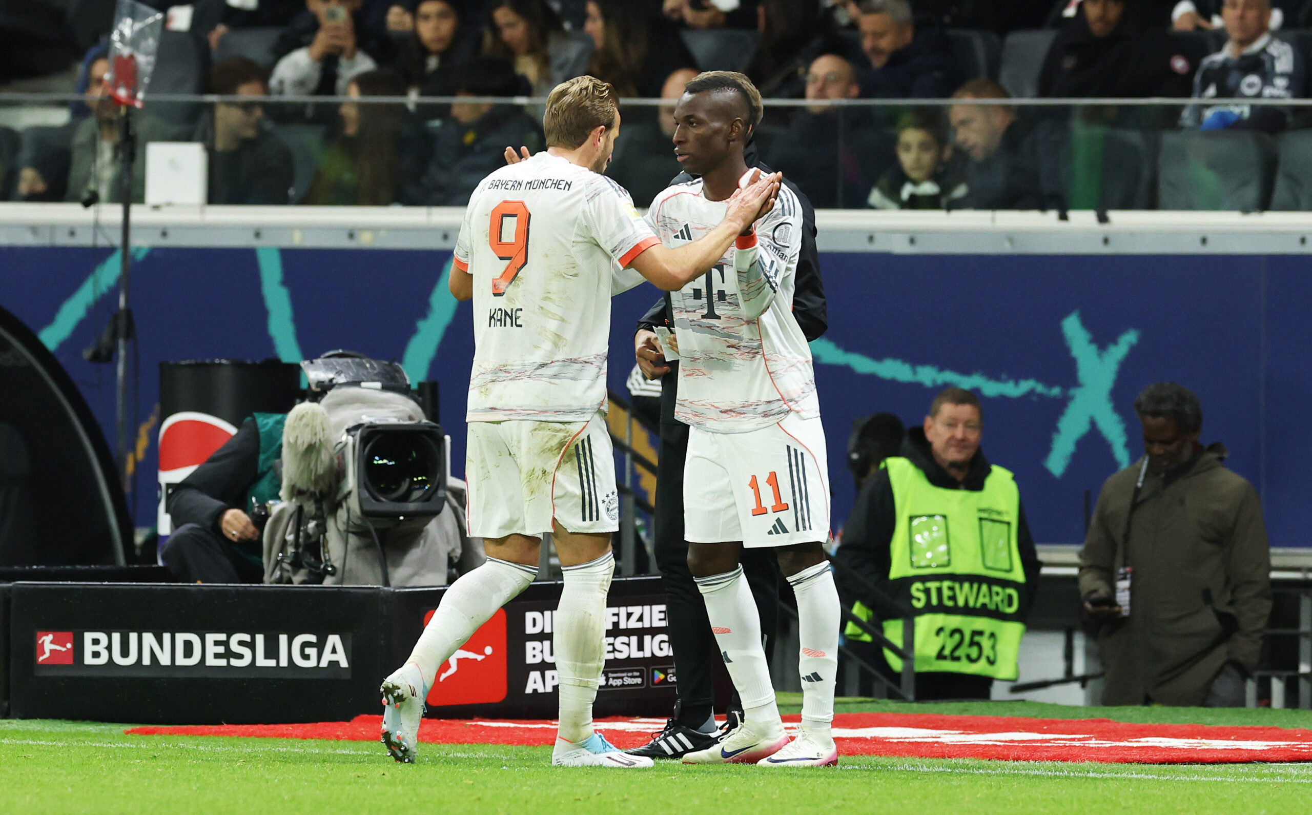 Harry Kane und Nicolas Jackson bei einer Auswechslung im Spiel zwischen dem FC Bayern und Eintracht Frankfurt. Beide klatschen sich ab.