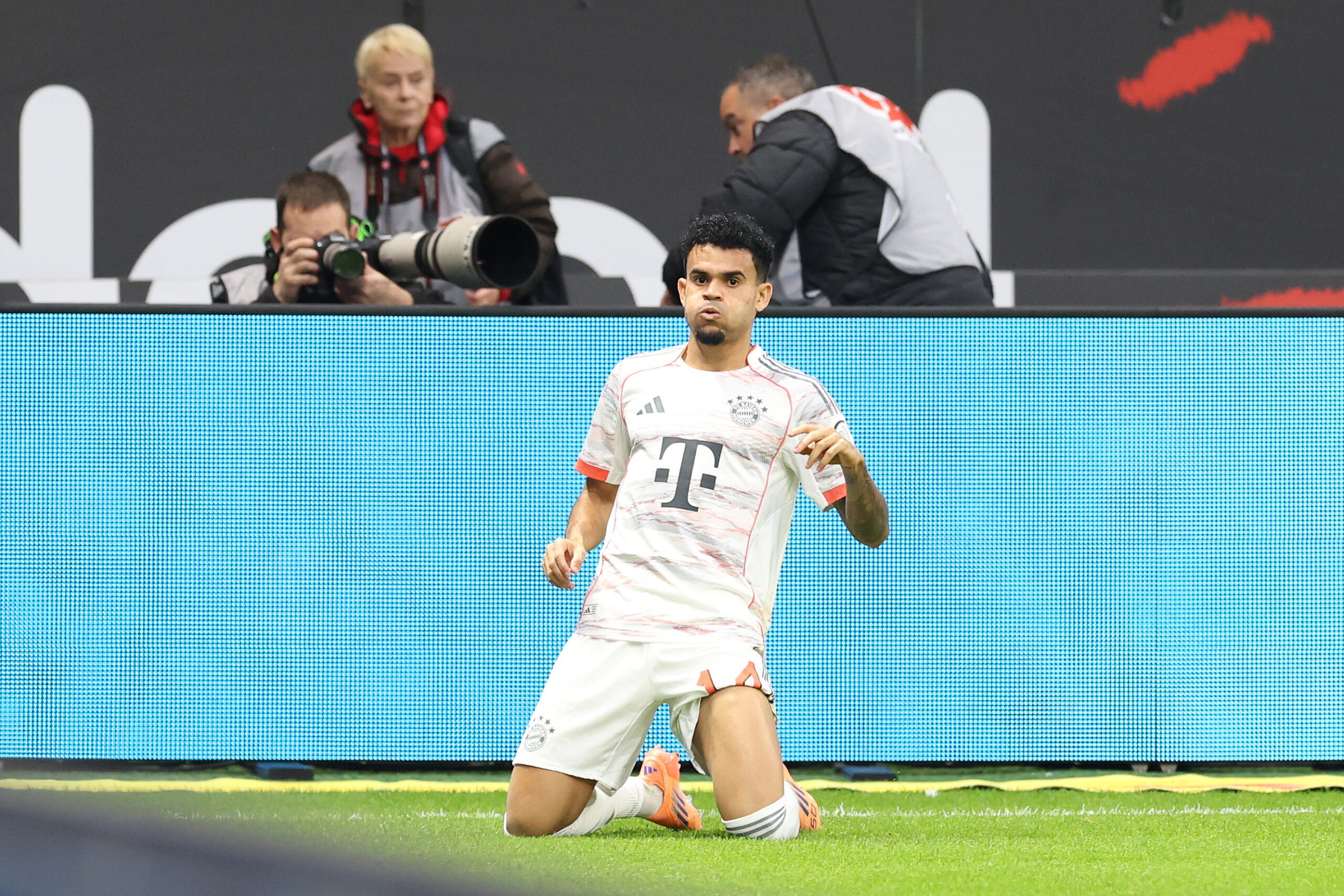 Luis Díaz auf den Knien im weißen Trikot des FC Bayern München.