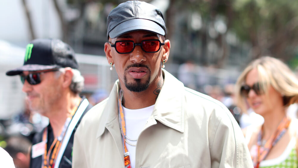 Jérôme Boateng (ehemals FC Bayern) in Zivilkleidung bei einem Formel-1-Event. Er trägt helle Oberteile, eine dunkle Mütze und eine rote Brille.