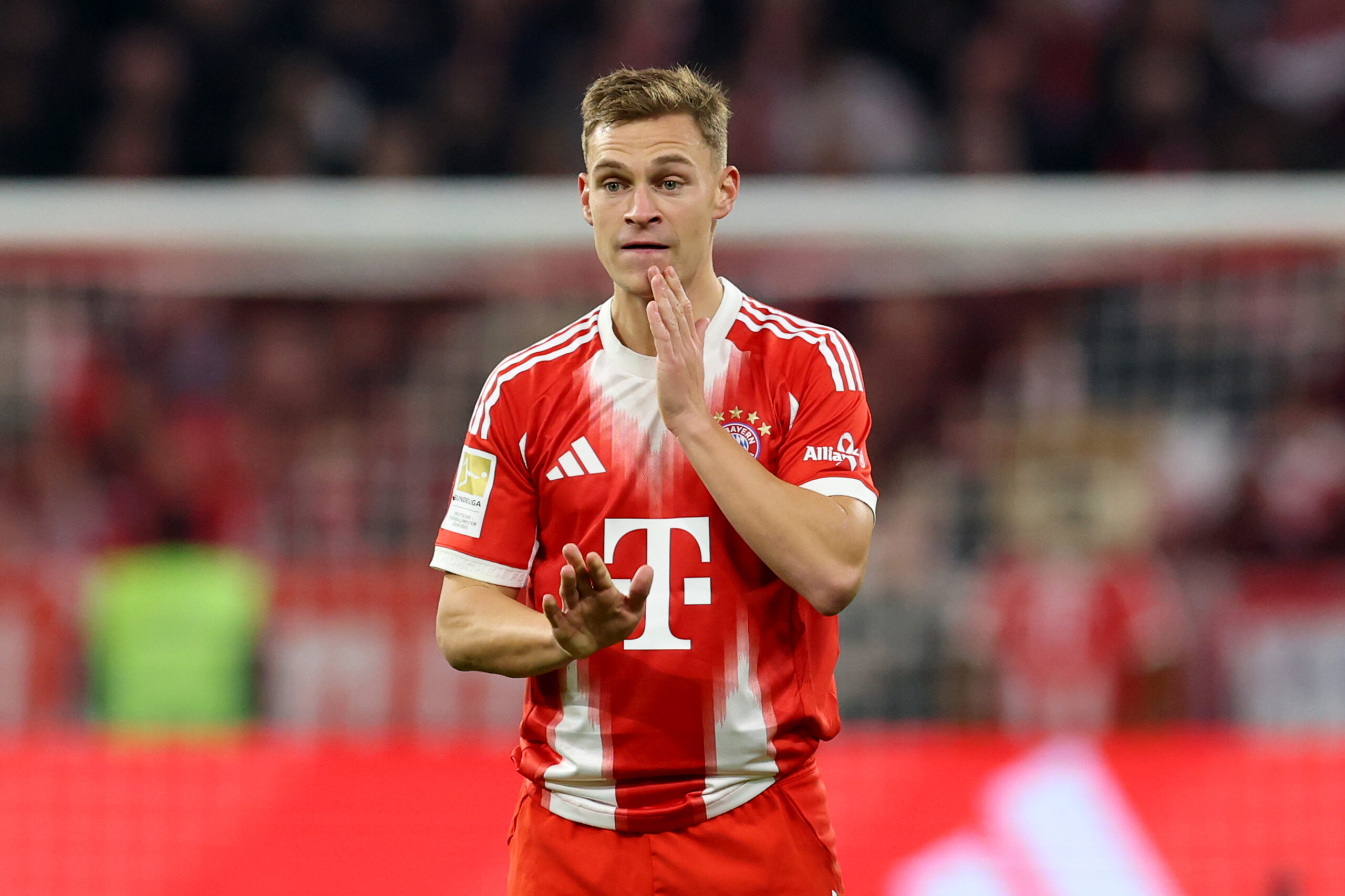 Joshua Kimmich vom FC Bayern München fässt sich ins Gesicht und schaut etwas unsicher.