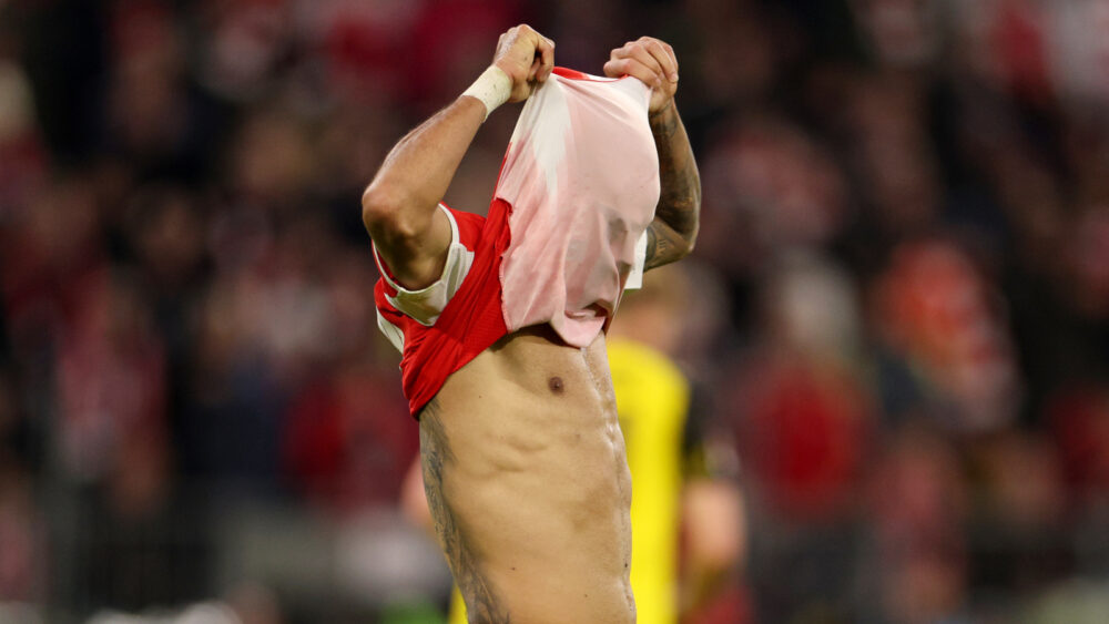 Luis Díaz zieht sich das Trikot des FC Bayern über den Kopf.