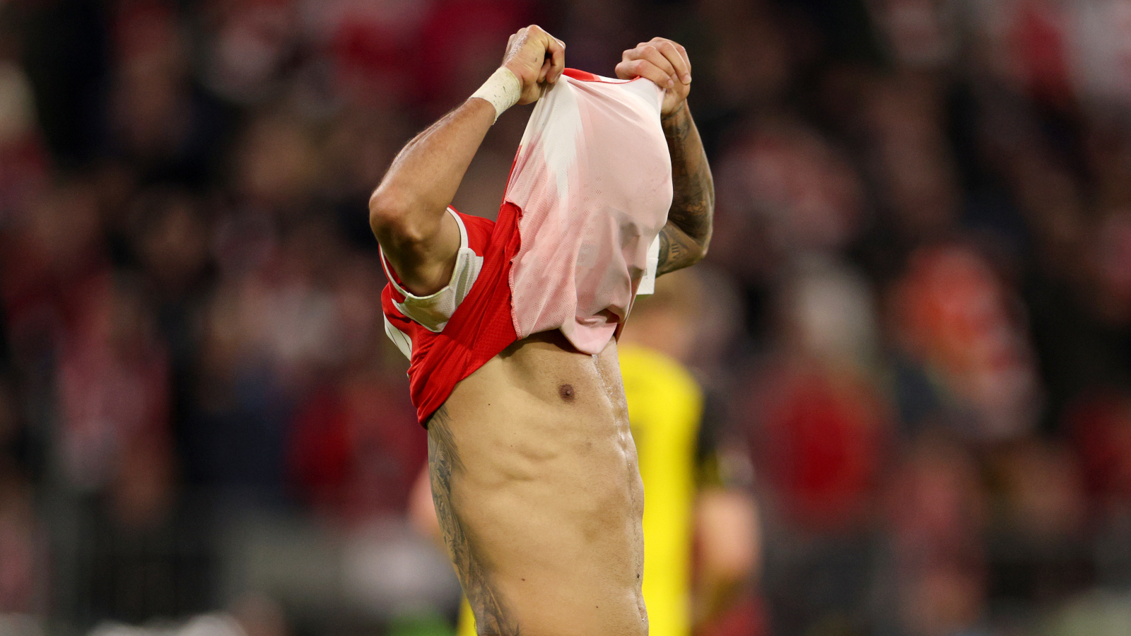 Luis Díaz zieht sich das Trikot des FC Bayern über den Kopf.