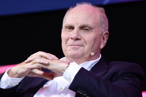 Uli Hoeneß nimmt die Hände vor dem Gesicht zusammen und lächelt zufrieden.