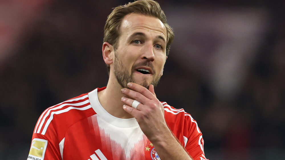 Harry Kane vom FC Bayern München fasst sich ans Kinn und schaut skeptisch.