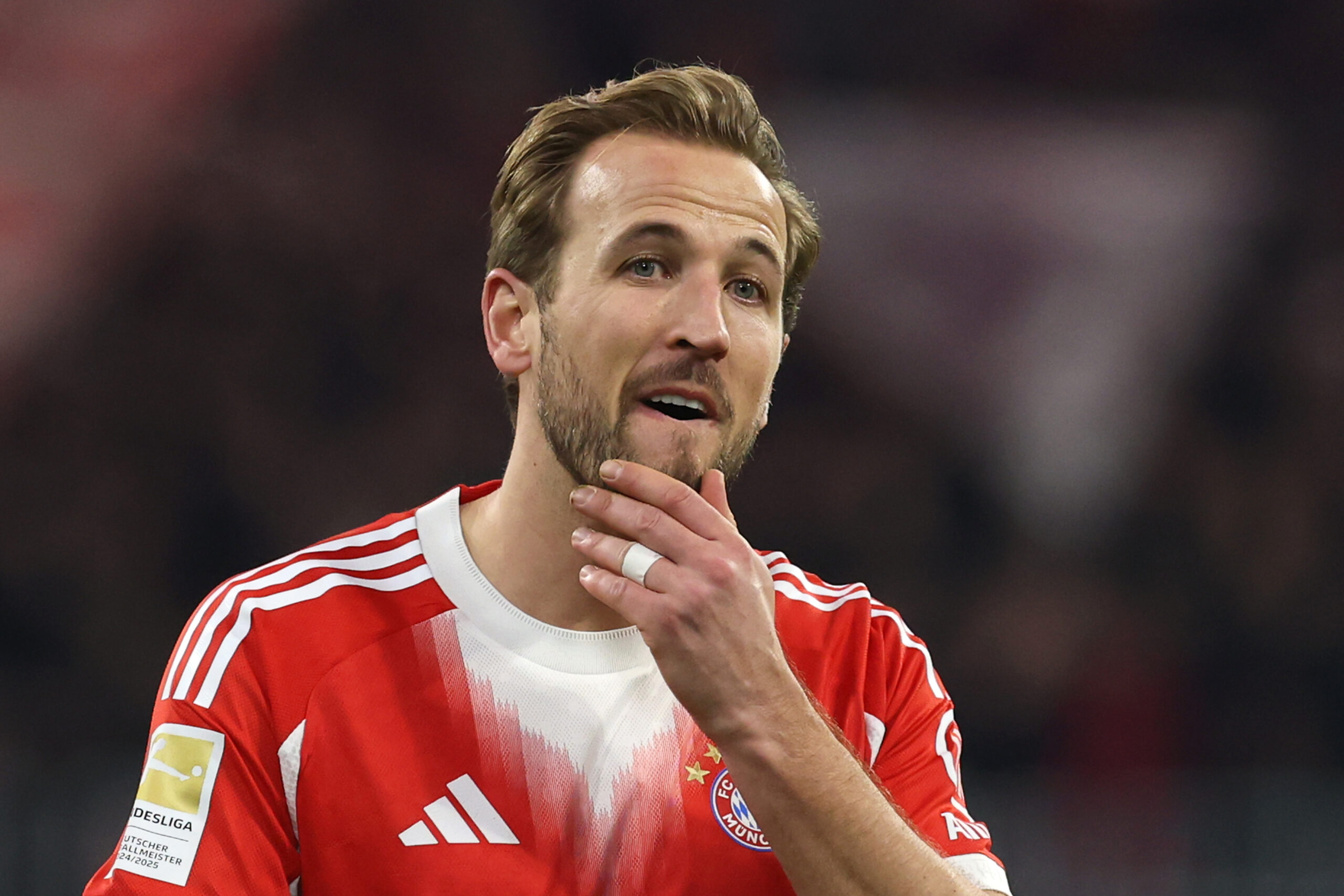 Harry Kane vom FC Bayern München fasst sich ans Kinn und schaut skeptisch.