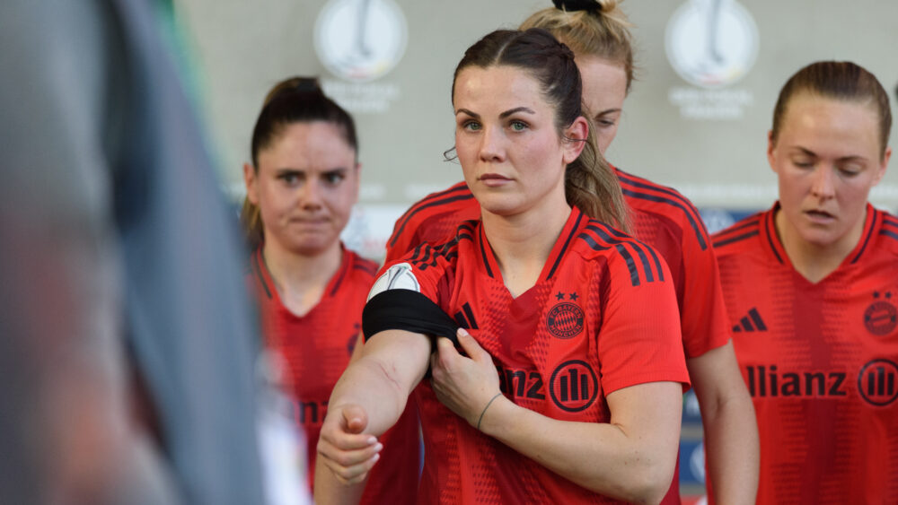 Tuva Hansen zieht sich die schwarze Binde über den Ärmel ihres roten Trikots von den FC Bayern Frauen.