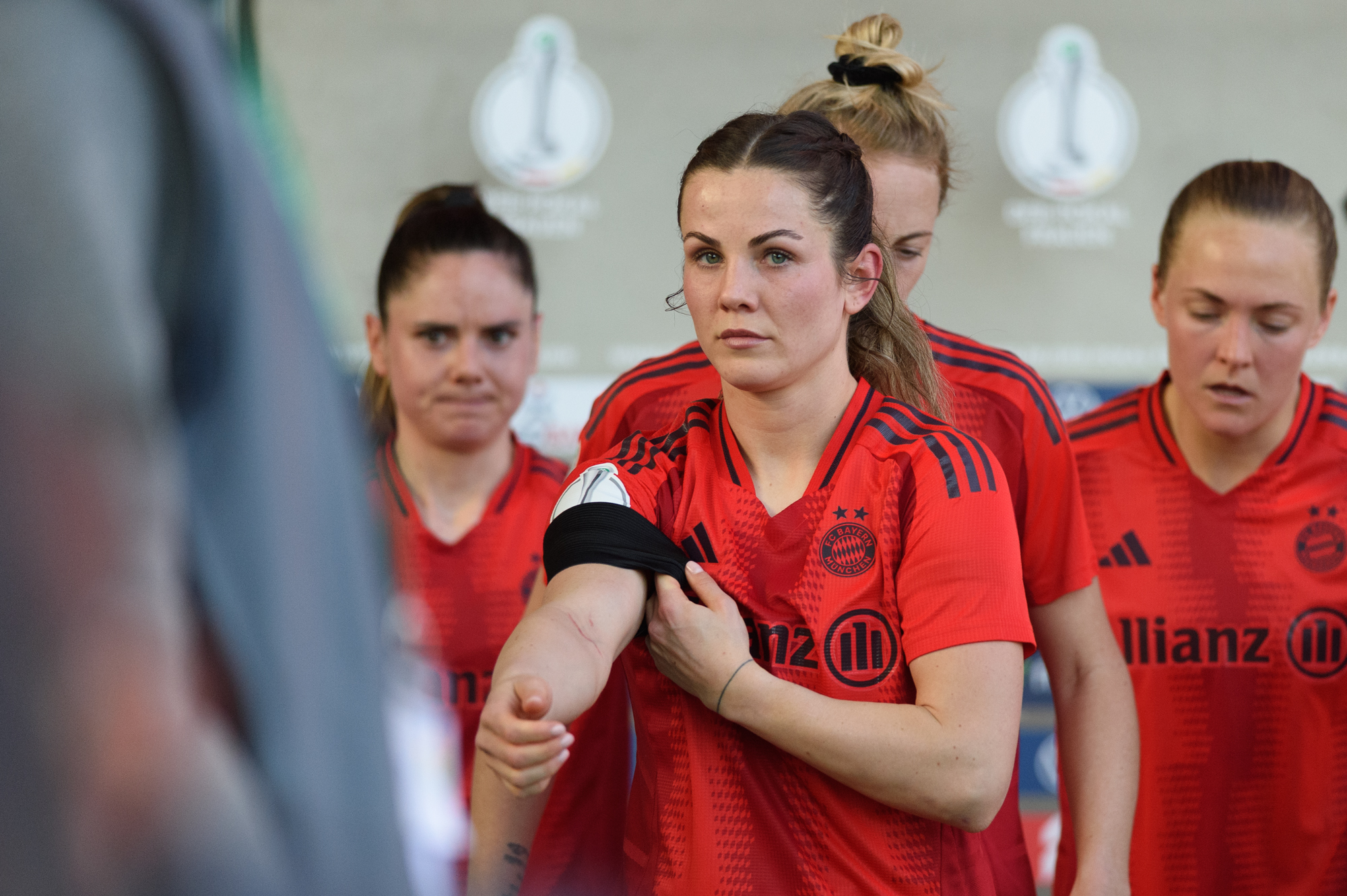 Tuva Hansen zieht sich die schwarze Binde über den Ärmel ihres roten Trikots von den FC Bayern Frauen.
