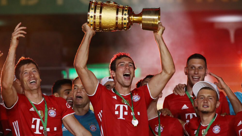 Leon Goretzka (FC Bayern) hebt den DFB-Pokal in den Nachthimmelt von Berlin und schreit.