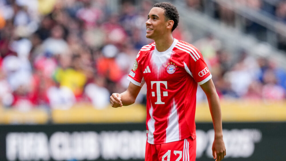 Jamal Musiala im Trikot des FC Bayern. Er schaut leicht nach oben und lächelt.