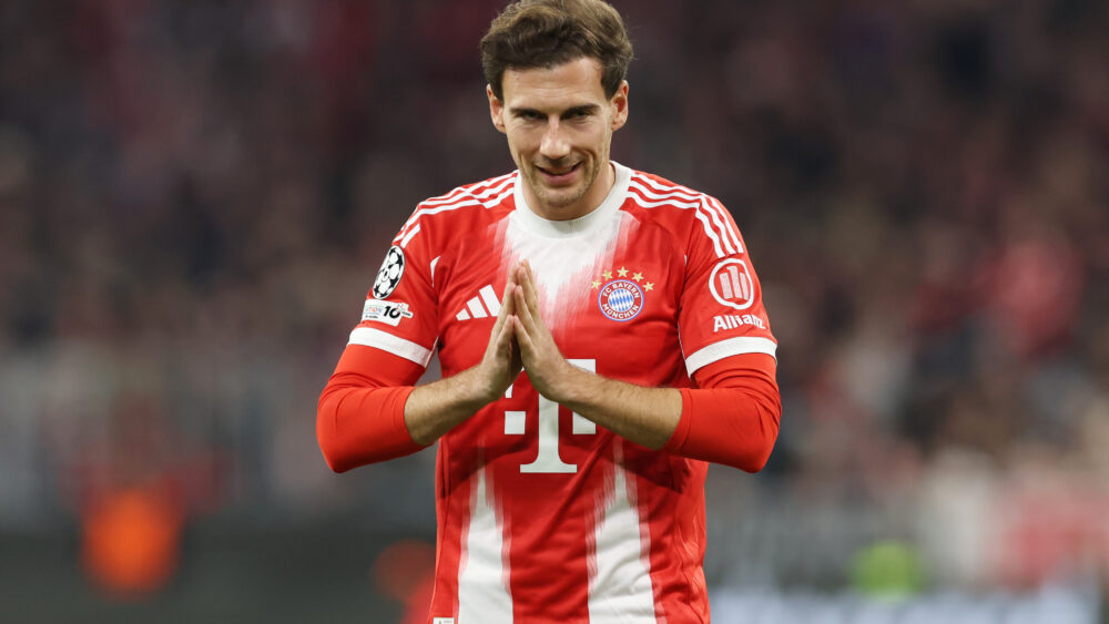 Leon Goretzka (FC Bayern) schaut lächelnd nach vorn und drückt die Fingerspitzen beider Hände aneinander.