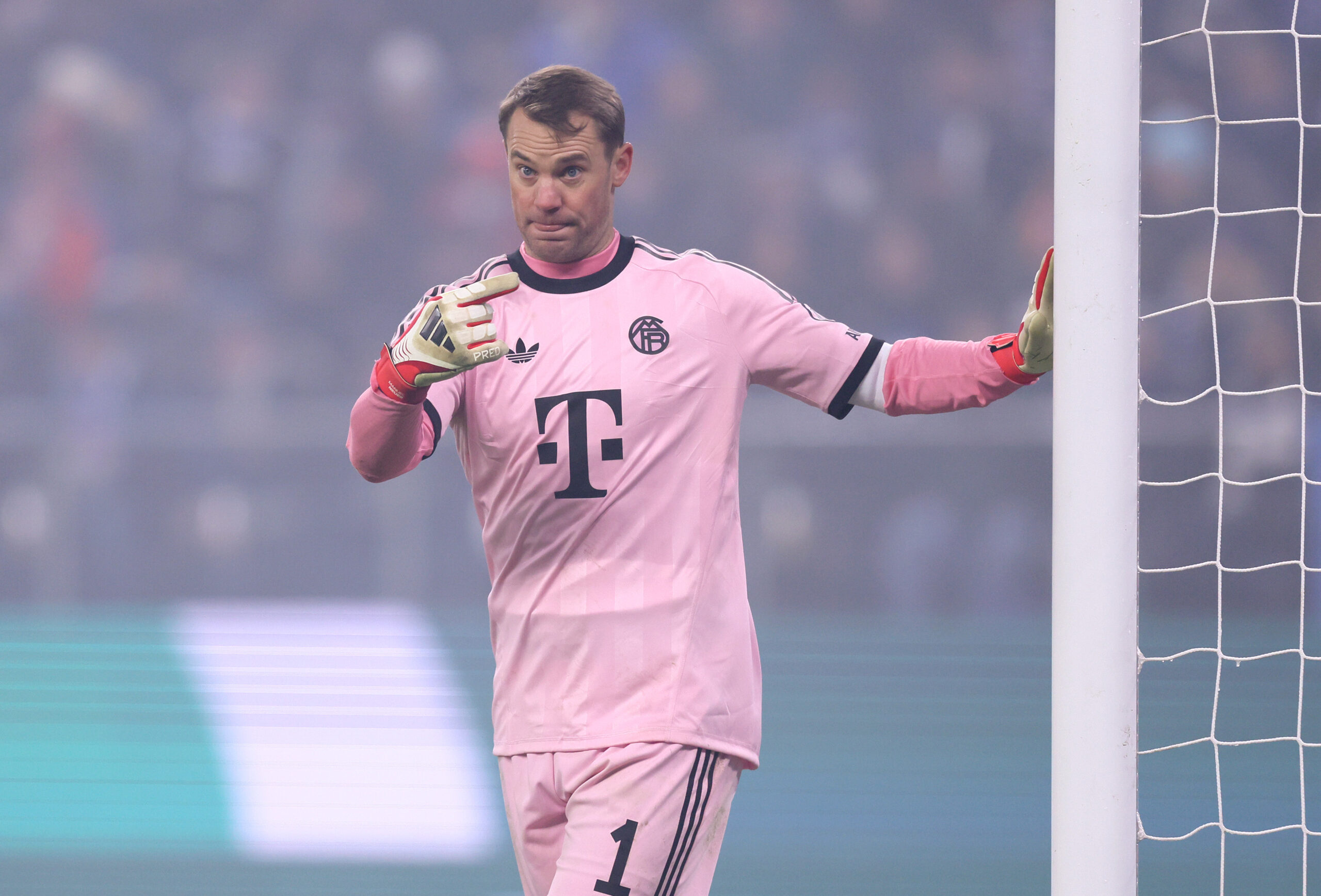 Manuel Neuer im rosafarbenen Trikot des FC Bayern. Er zeigt mit dem Finger in Richtung Pfosten.