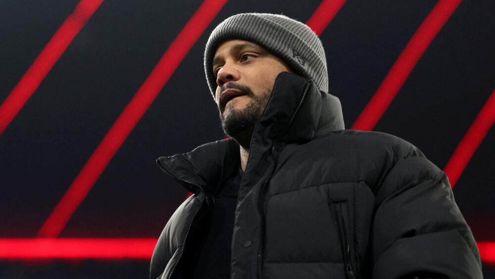 Vincent Kompany vom FC Bayern München. Die Aufnahme zeigt ihn von unten, im Hintergrund ist das Dach der Allianz Arena zu sehen.