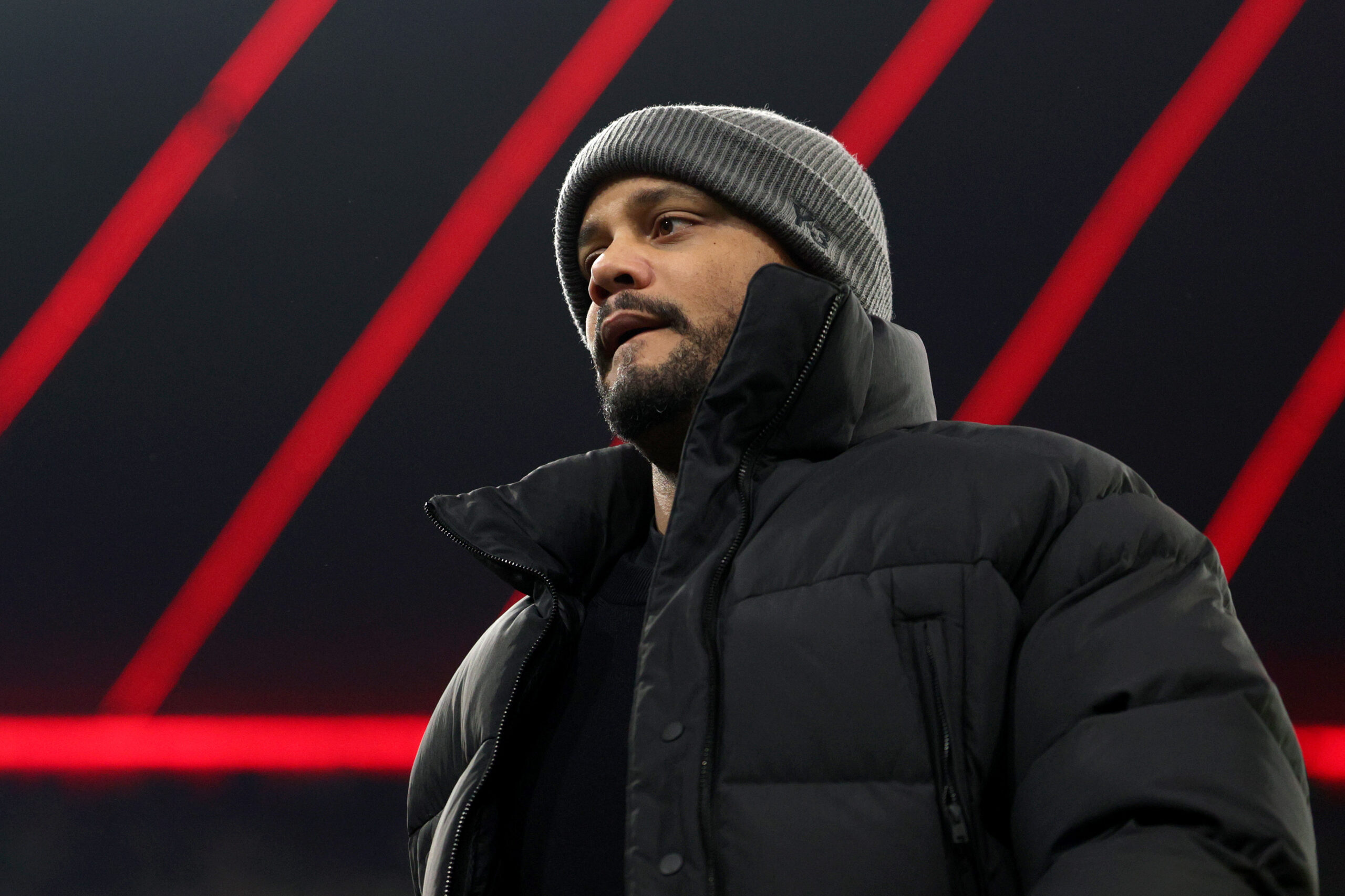 Vincent Kompany vom FC Bayern München. Die Aufnahme zeigt ihn von unten, im Hintergrund ist das Dach der Allianz Arena zu sehen.