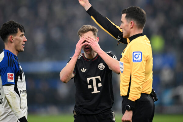 Harm Osmers zeigt eine Gelbe Karte, Joshua Kimmich vom FC Bayern schlägt die Hände vor dem Gesicht zusammen.