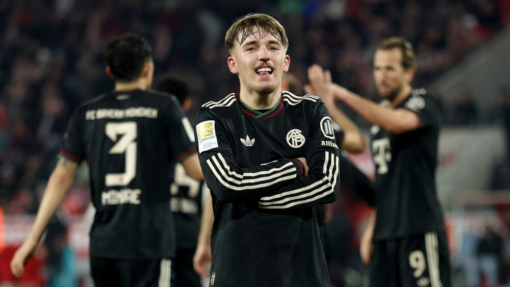 Lennart Karl verschränkt die Arme und grinst. Er jubelt über ein Tor für den FC Bayern.