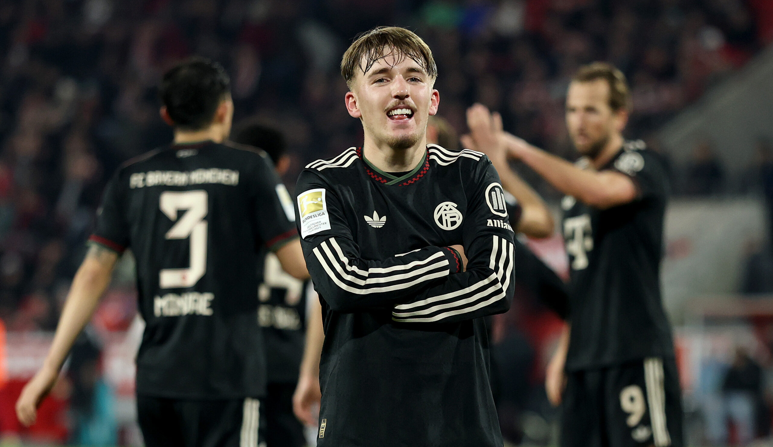 Lennart Karl verschränkt die Arme und grinst. Er jubelt über ein Tor für den FC Bayern.