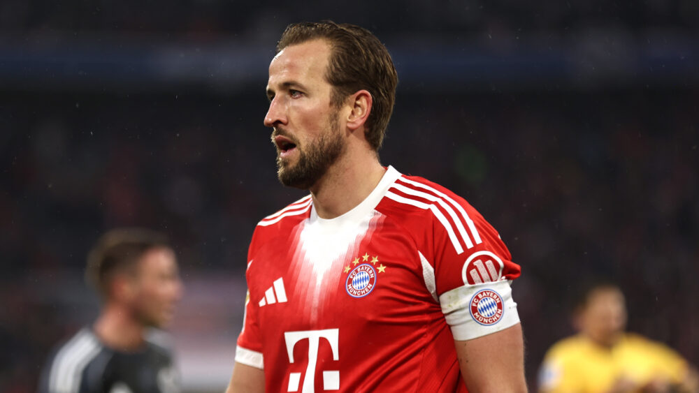 Harry Kane vom FC Bayern in der Portraitaufnahme, etwas seitlich. Er schaut etwas fassungslos und trägt die Kapitänsbinde des FCB.