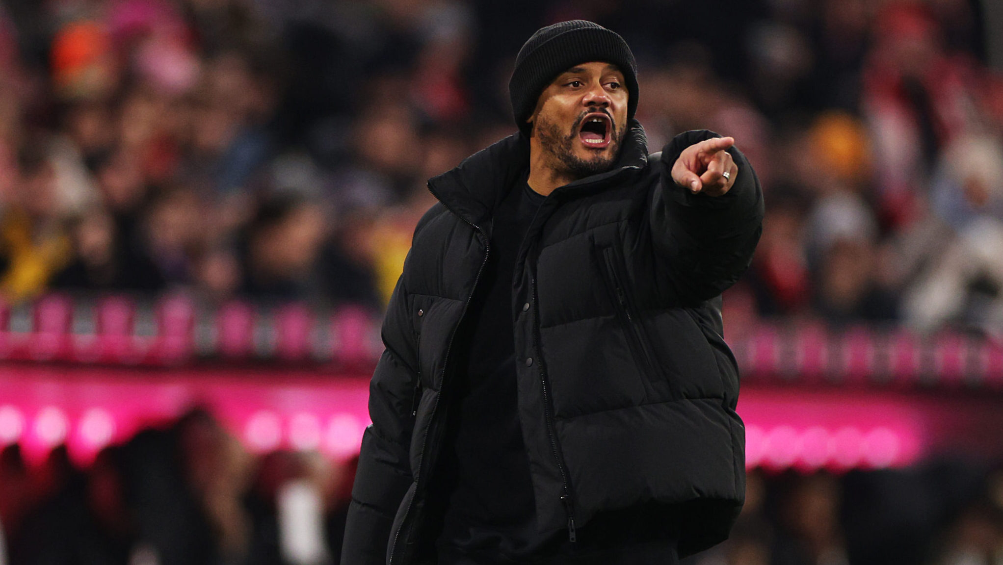 Vincent Kompany (FC Bayern) zeigt mit seinem linken Arm auf etwas.