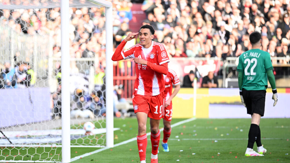 Jamal Musiala jubelt über ein Tor für den FC Bayern gegen den FC St. Pauli und zeigt sich auf den Kopf.