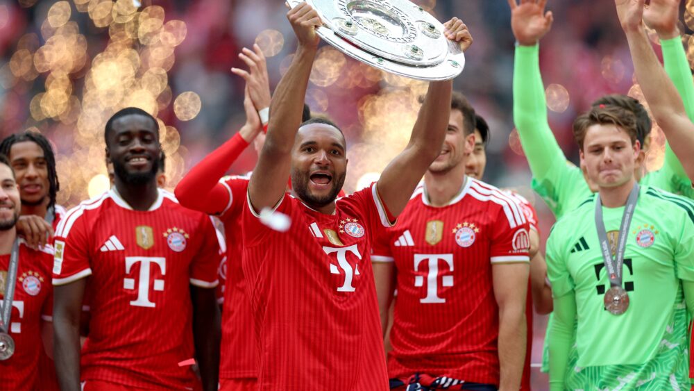 Jonathan Tah hebt die Meisterschale in die Luft, die er mit dem FC Bayern gewonnen hat.