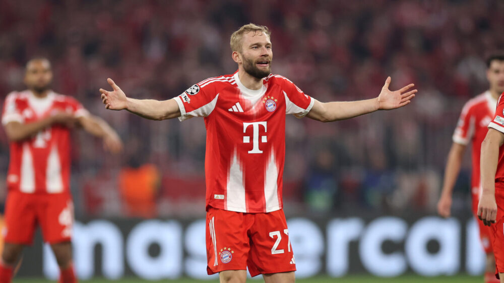 Konrad Laimer streckt die Arme fragend zur Seite aus. Er trägt das rot-weiße Trikot des FC Bayern.
