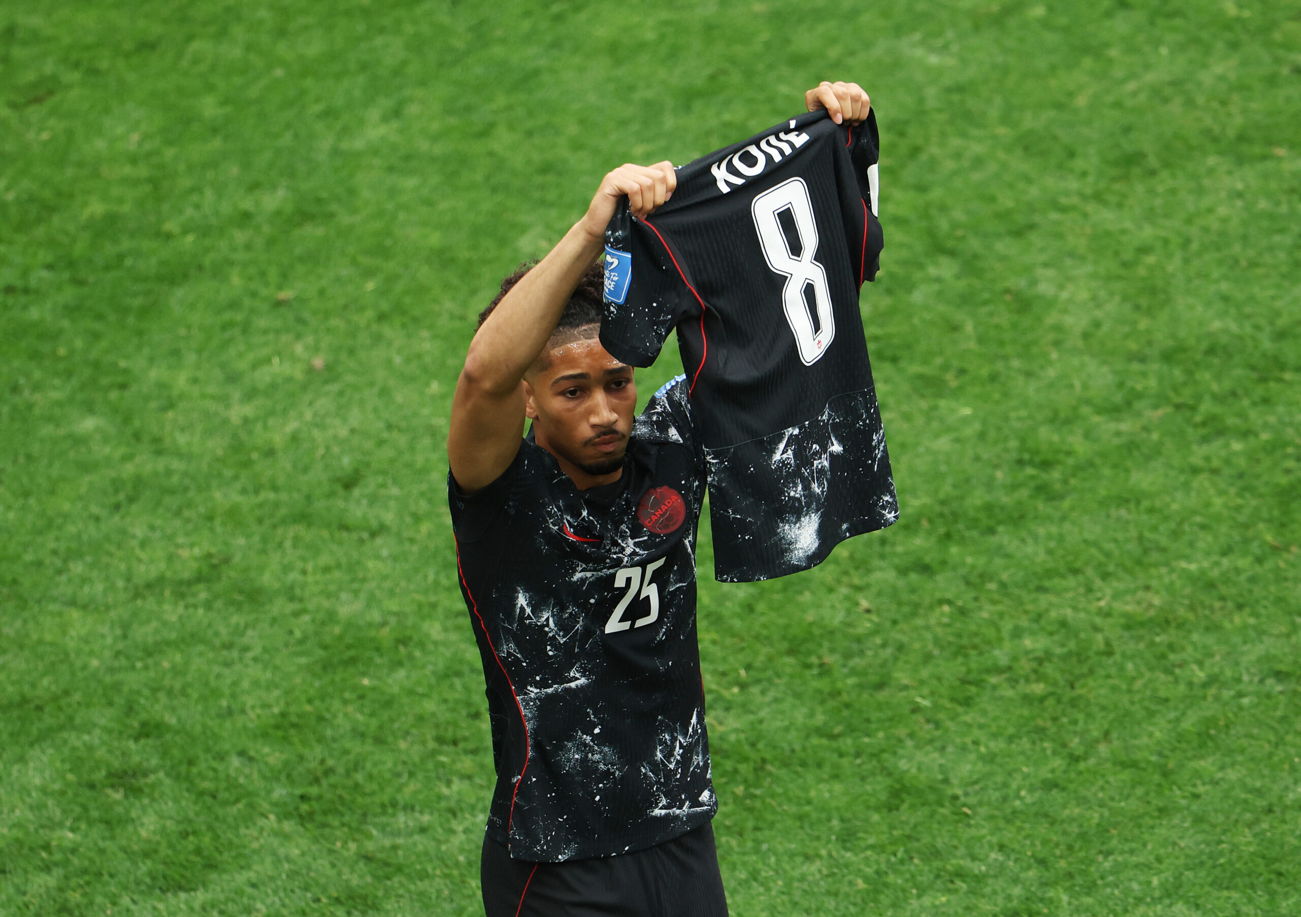 Saliba hält das Trikot von Teamkollege Koné in die Luft. Der hatte sich bei der WM 2026 schwer verletzt und wird Kanada fehlen.