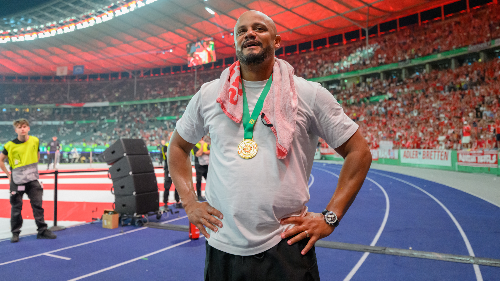 Vincent Kompany (FC Bayern) mit den Händen in der Hüfte und der goldenen DFB-Pokal-Medaille um den Hals. Er sieht sehr glücklich und erleichtert aus.