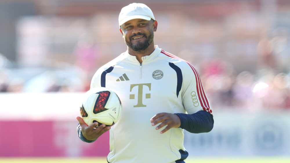 Vincent Kompany (FC Bayern) mit einem Ball in der Hand und lächelnd.