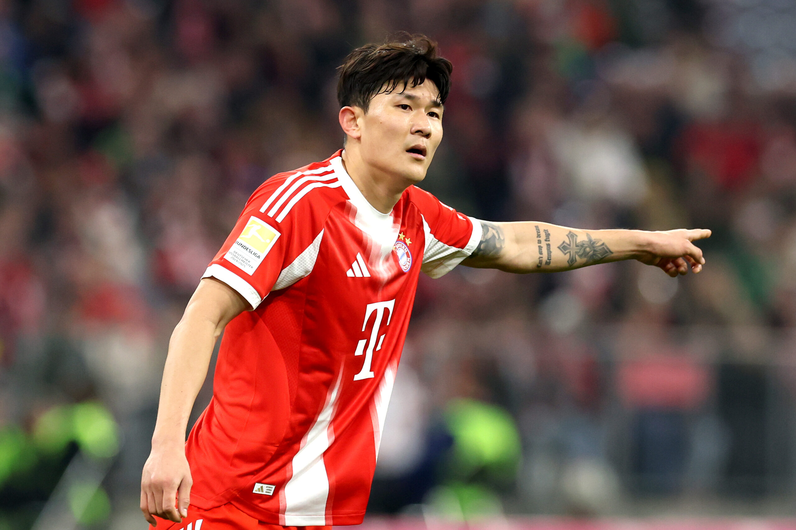 Min-jae Kim im Trikot des FC Bayern. Er zeigt mit dem linken Arm zur Seite.