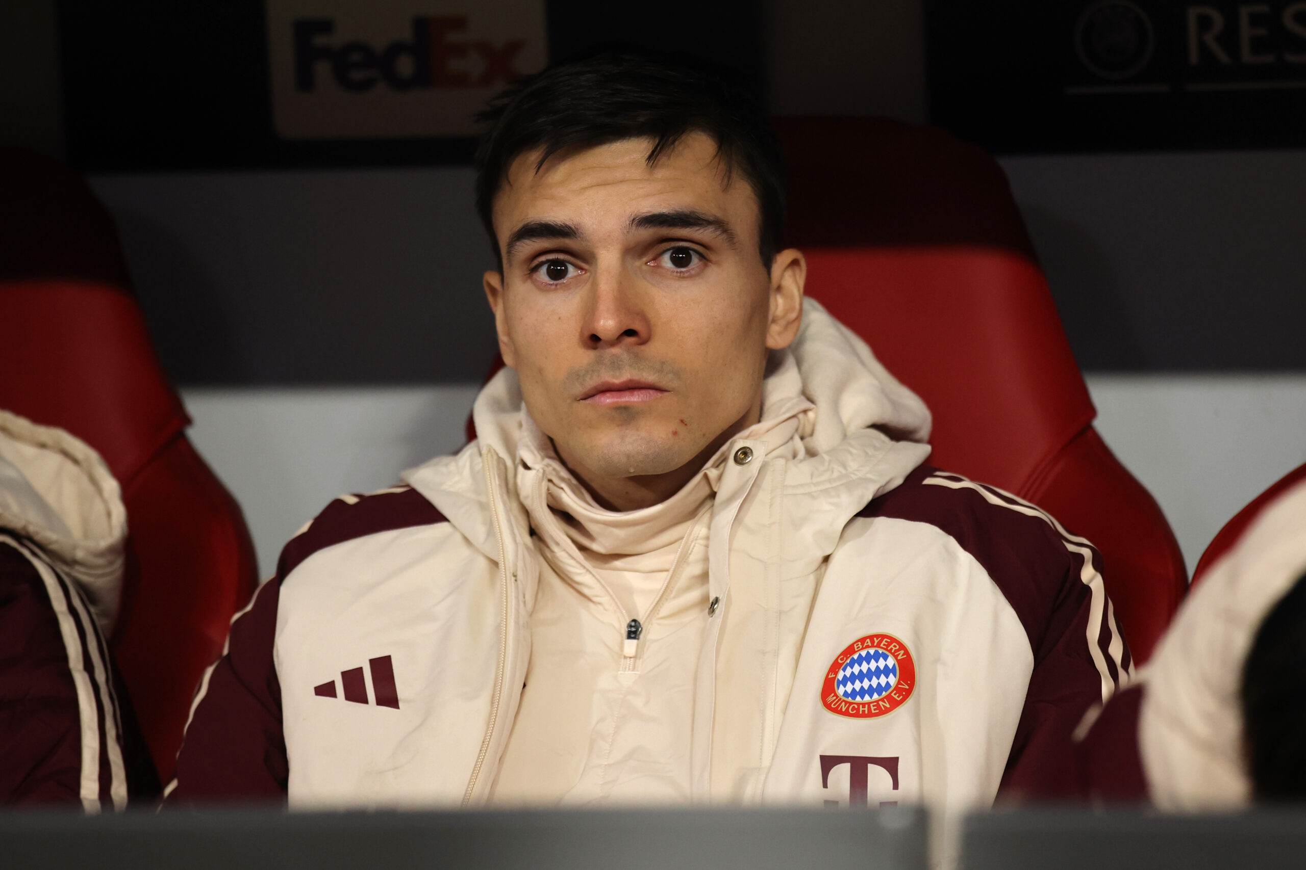 Joao Palhinha (FC Bayern) schaut nach vorne in einer weißen Jacke.