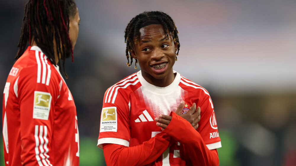Wisdom Mike (FC Bayern) lächelt und kreuzt die Arme auf der Brust.