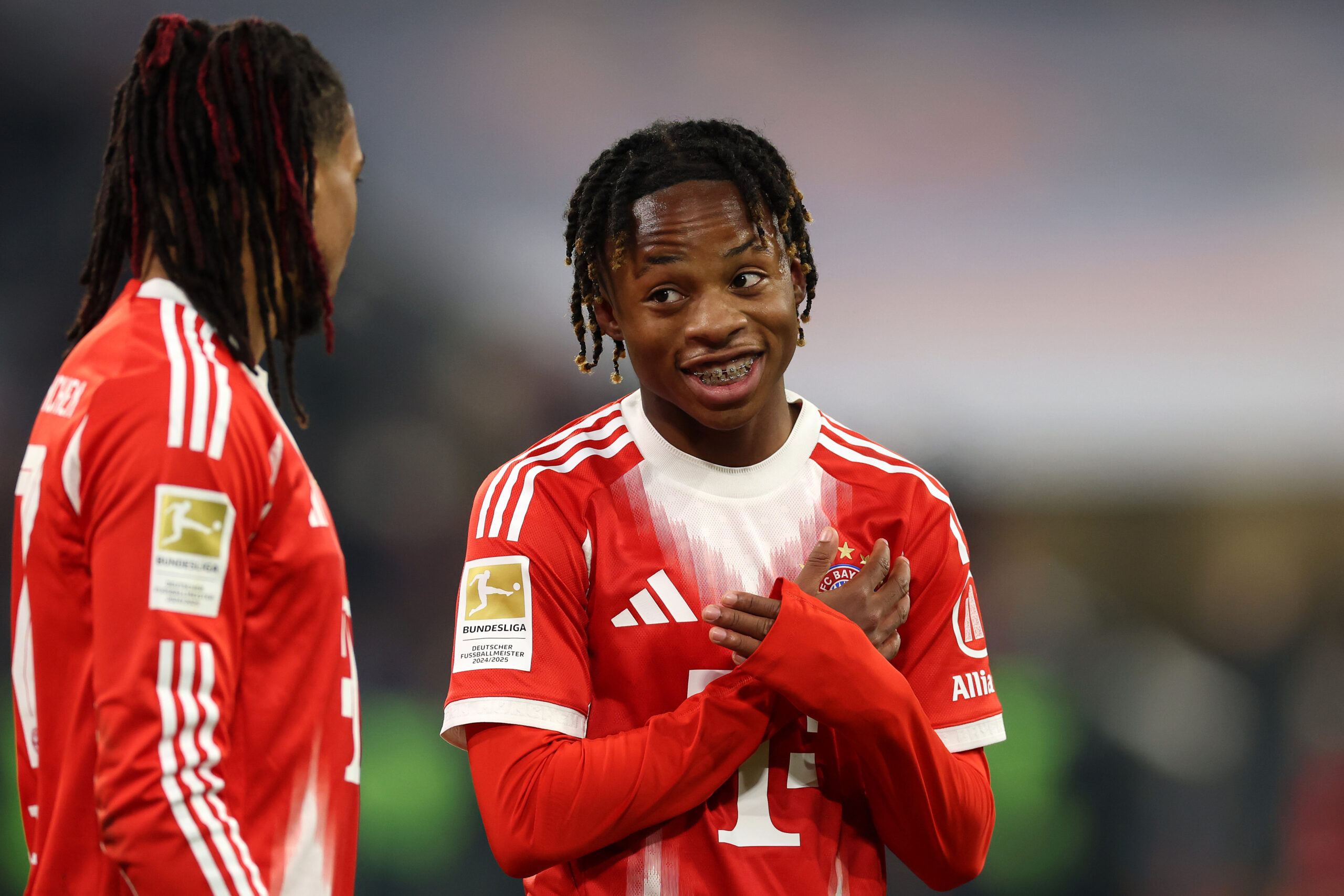 Wisdom Mike (FC Bayern) lächelt und kreuzt die Arme auf der Brust.