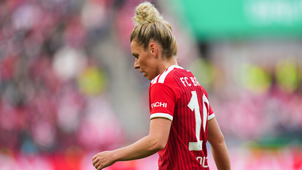 Linda Dallmann, Seitenansicht, trägt das rote Trikot des FC Bayern und schaut leicht nach unten.